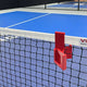Indoor pickleball court with a red net clip on a blue court surface.